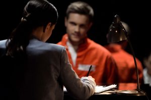 Broward criminal defense lawyer talking to criminal defendant in orange jumpsuit